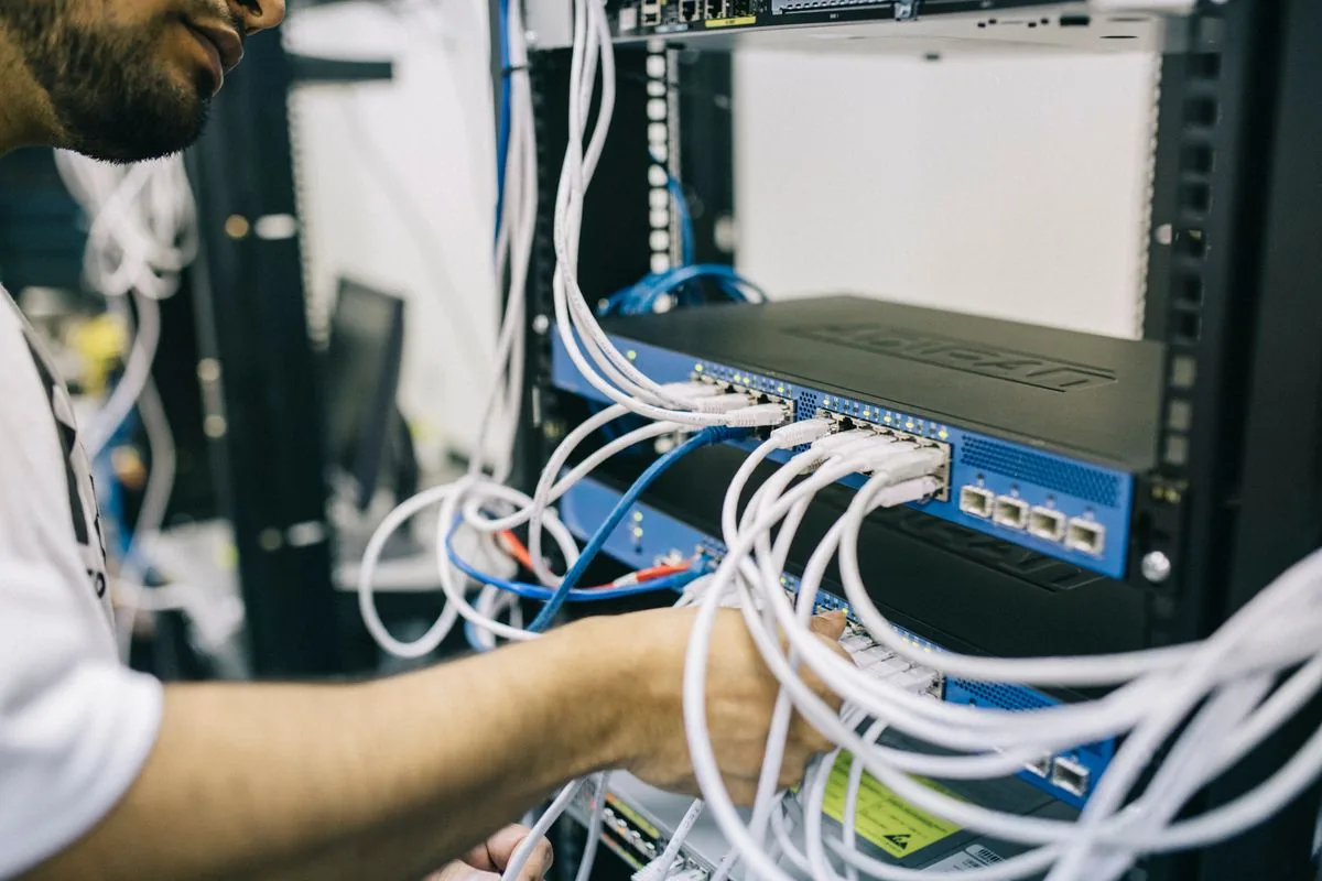 Técnico conectando cables de red en un rack de comunicaciones